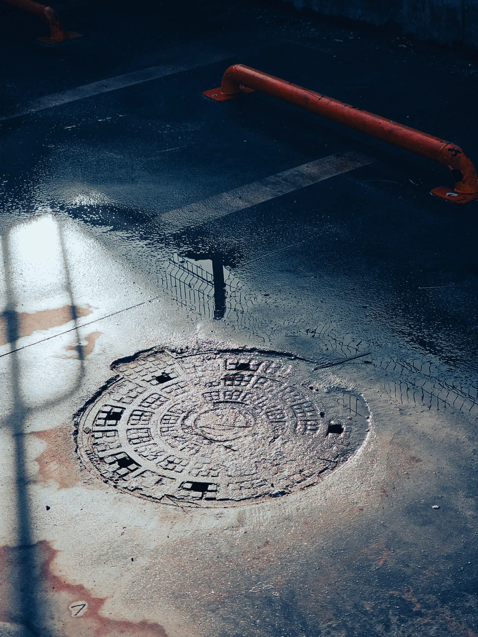 Cast-iron waterworks manhole cover on a wet access road